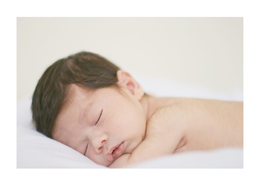 Newborn baby peacefully sleeping on a white blanket during an in-home session with Palo Alto newborn photographer Isela Lozano