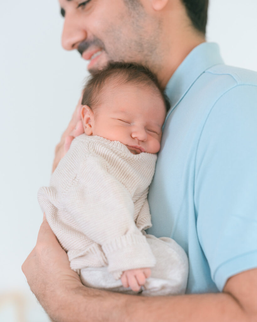 7-day-old newborn sleeping on dad’s chest, dad wearing light blue polo shirt, smiling, natural at-home Mill Valley newborn photography