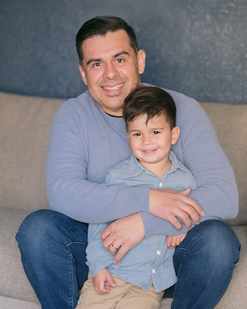 Father and son sitting at the edge of the couch sharing a quiet hug in their Palo Alto home