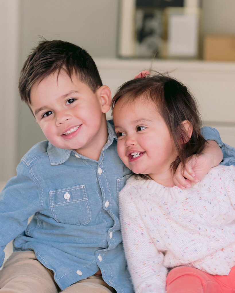 Two toddle siblings brother and sister sitting on the bed hugging and smiling. Captured by Palo Alto Family Photographer