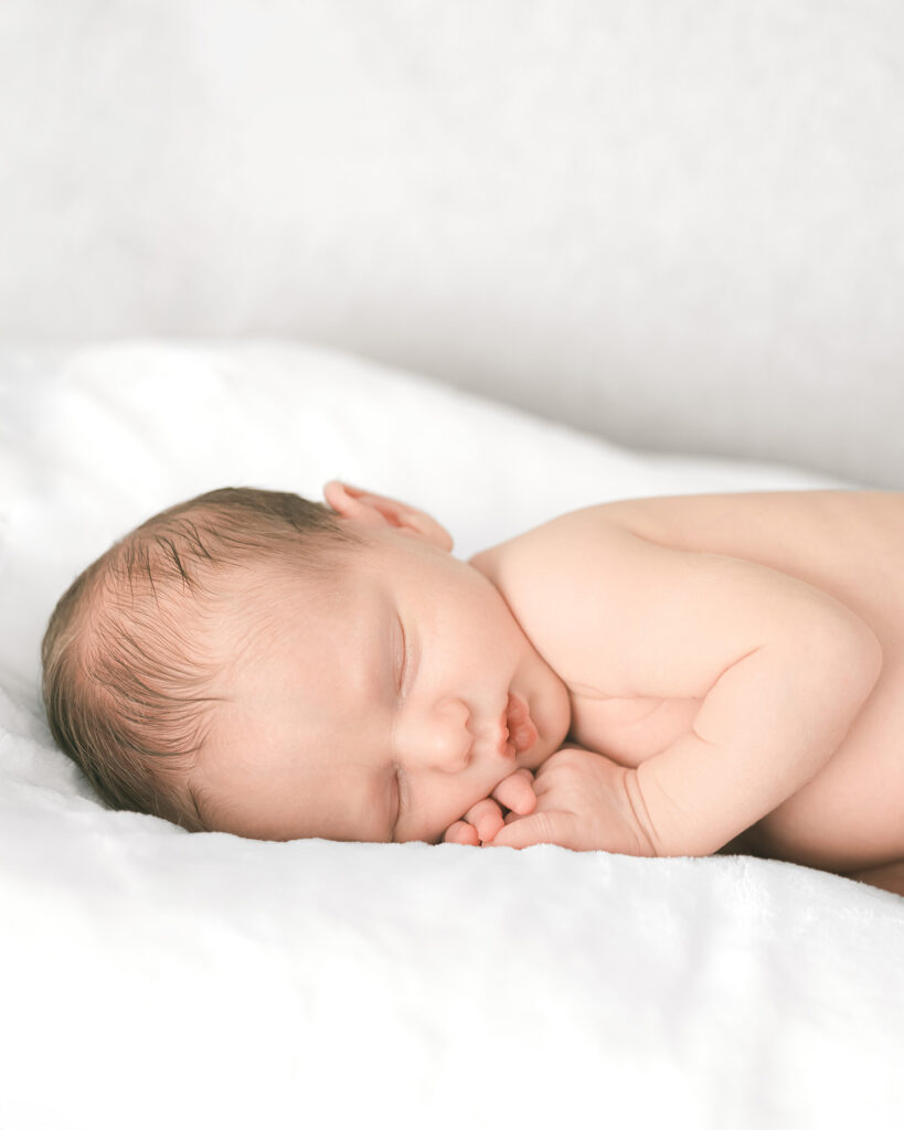 Newborn baby sleeping on the bed wearing just a diaper during a natural in-home newborn photography session by Palo Alto photographer Isela Lozano.