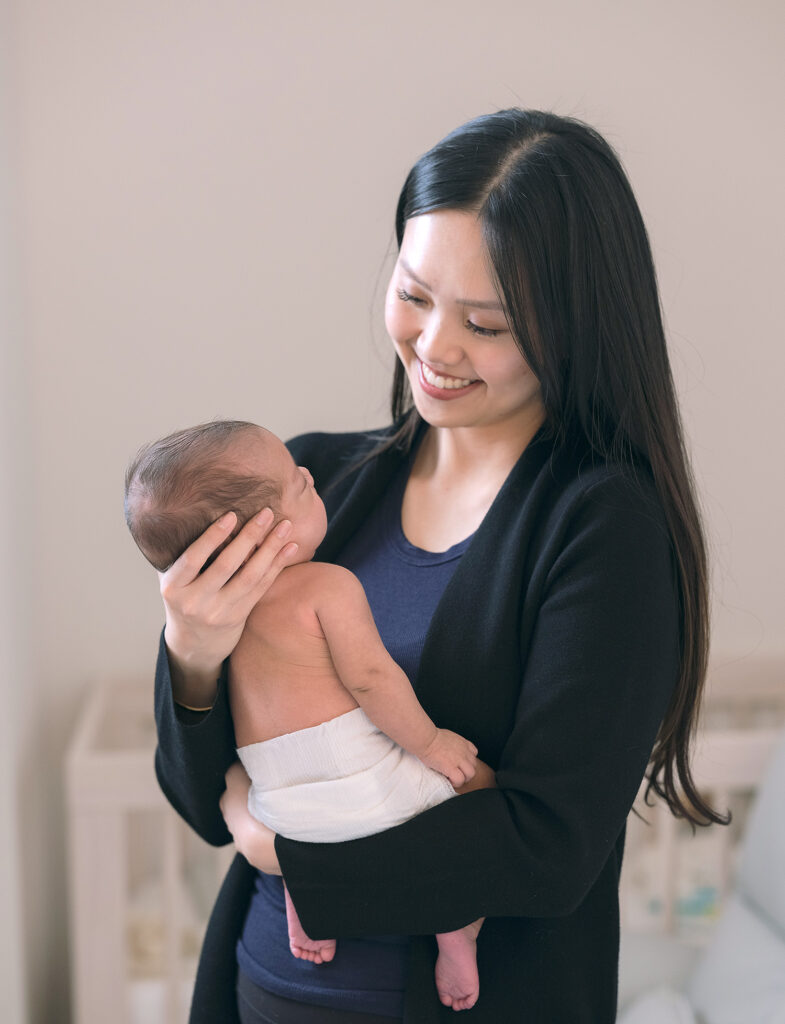 Mother smiling at newborn baby while baby looks up at her.